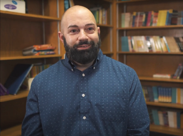  man with beard in dark blue shirt smiling at camera